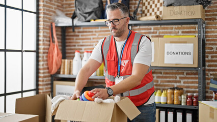 Grey-haired man volunteer packing toys to donate at charity center