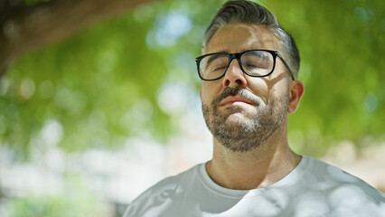 Grey-haired man breathing with closed eyes at park