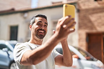 Young hispanic man smiling confident having video call at street