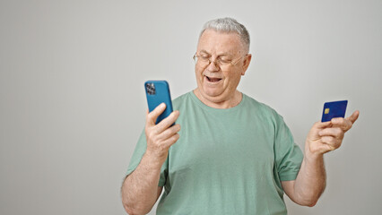 Middle age grey-haired man shopping with smartphone and credit card surprised over isolated white background