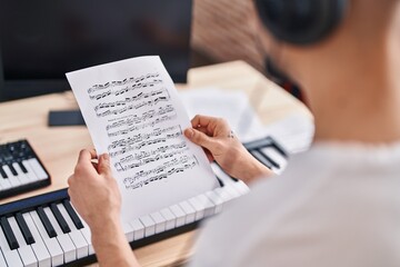 Young arab man musician reading music sheet at music studio