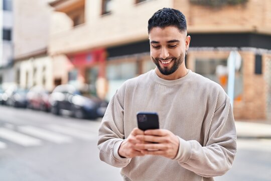 Young arab man smiling confident using smartphone at street