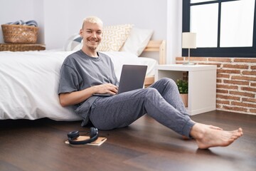 Young caucasian man using laptop sitting on floor at bedroom