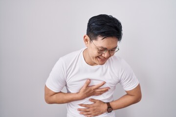 Young asian man standing over white background smiling and laughing hard out loud because funny crazy joke with hands on body.