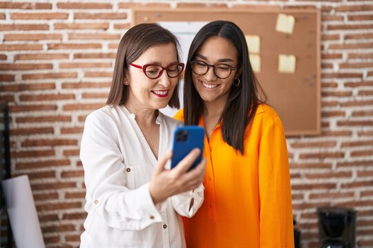 Two women business workers using smartphone working at office
