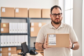 Plus size hispanic man with beard working at small business ecommerce skeptic and nervous, frowning upset because of problem. negative person.