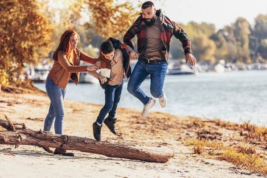 Parents and son walking near river spending vacation in countryside