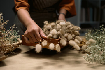 Cropped shot of florist making a bouquet of dried flowers at her workstation. Small business concept