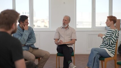 Panning shot of confident mature male mentor corporate leader communicating with multiracial business professional team, teaching interns staff group engaged in discussion at training meeting, slowmo.