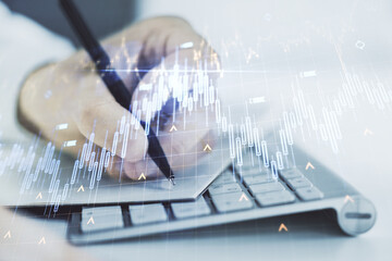 Multi exposure of abstract creative financial chart with world map and with hand writing in notebook on background with laptop, research and analytics concept