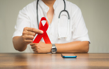 World AIDS Day. Close-up of hand holding a red ribbon symbol.