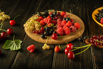 Fresh berries of strawberries, currants, raspberries and cherries on a dark kitchen table before making fruit drink or compote. Vegetarian diet concept