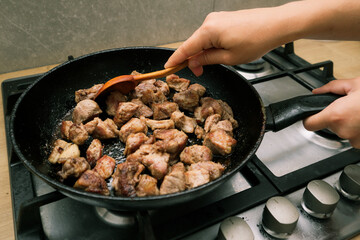 Woman mixing the meat in a frying pan shovel. Pan-fried meat, French fries