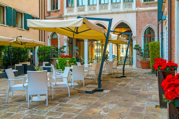 Fototapeta na wymiar Romantic outdoor restaurant in Venice, Italy in a sunny day at sunrise