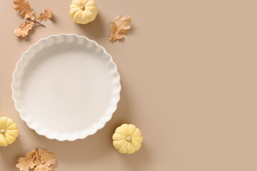 Thanksgiving Day background with empty plate for cook American Pumpkin Pie on beige background. View from above. Copy space.