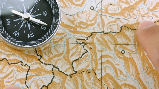 Close up male finger following route on blank map with compass
