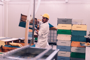 man in the honey shop arranges the beehives on the extractor machine