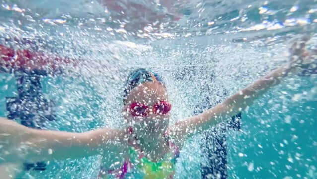 Child girl or teenager swims underwater in the pool. Shooting a video underwater as a child swims in a pool