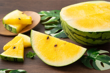 Sliced yellow watermelon in a plate on wooden table background.