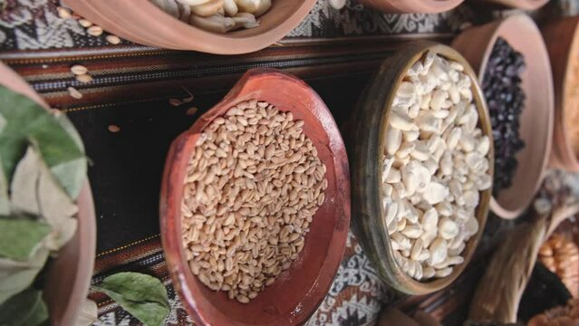 Various dried spices, andean cereals and grains in small bowls and raw herbs, andean peruvian culture