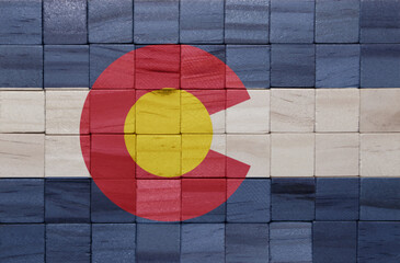 colorful painted big national flag of colorado state on a wooden cubes texture.