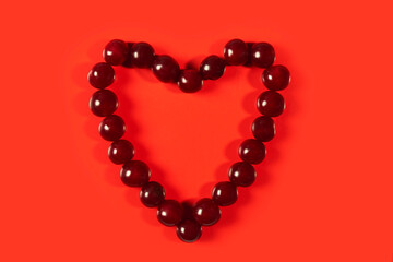 ruby cherry heart on a red background, a symbol of love and passion