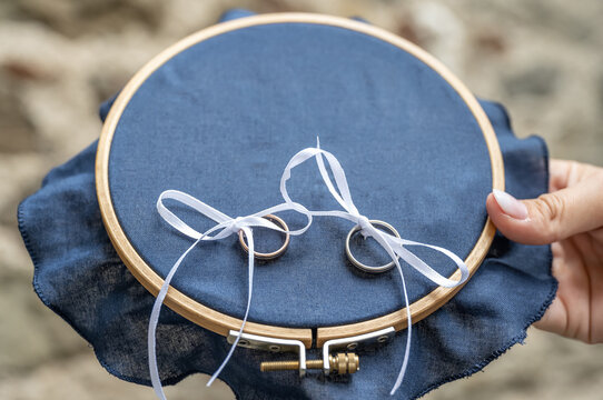 Close-up view of golden wedding rings on blank decorative stiching ring pillow