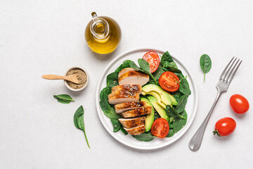 BBQ chicken fillet with spinach salad, tomatoes and avocado. Healthy food top view on white background