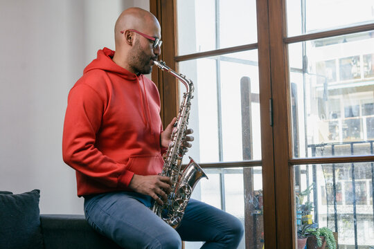 latino musician man at home playing the saxophone