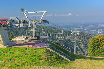 The upper station of the chairlift to Mała Czantoria in the Silesian Beskids (Poland) on a sunny summer day. In the distance, the buildings of Ustroń. - obrazy, fototapety, plakaty
