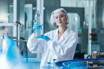 woman factory worker holding plastic bottle line manufacture drink water. female specialist factory...