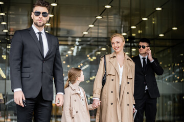 two bodyguards protecting successful woman and kid, private security, happy blonde mother and...