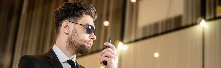 good looking bodyguard, security worker in suit and sunglasses working in lobby of hotel,...