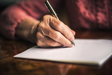 Senior woman write at the table. AI generated - obrazy, fototapety, plakaty