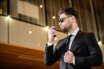 good looking bodyguard, security worker in suit and sunglasses working in lobby of hotel,...