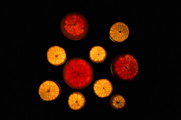 Sliced grapefruit and lemon lie on a skylight on a black background