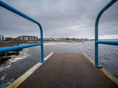 View on Salthill area from the top of Blackrock diving board. Galway city, Ireland. Popular town area with stunning view on Galway bay. Cloudy sky.