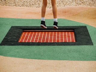 Small trampoline in a park and legs of teenager jumping high. Having fun outdoors concept. Sport...