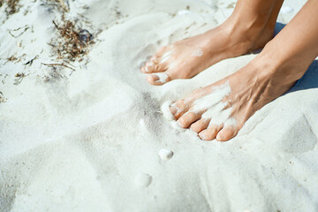 Close up shot of tanned feet on the white sands. Blissful beach vacation and summer vibes. Foot care and wellness