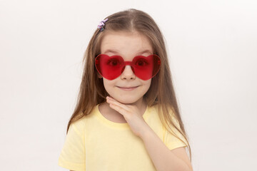 Portrait of surprised cute little toddler girl in the heart shape sunglasses. Child with open mouth having fun isolated over white background. Looking at camera. Wow funny face