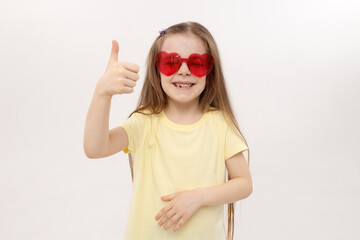 Portrait of surprised cute little toddler girl in the heart shape sunglasses. Child with open mouth having fun isolated over white background. Looking at camera. Wow funny face