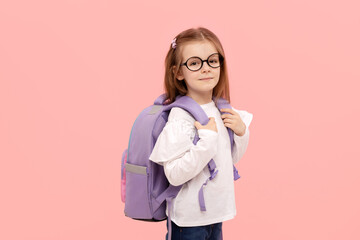 Portrait of a schoolgirl with textbooks and a backpack on a pink background. Back to school