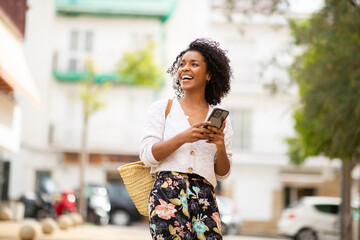 happy young african american woman with phone in city
