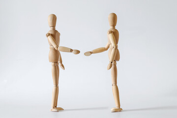two wooden people extend their hands to each other for a handshake