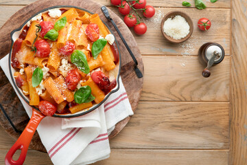 Pasta Tortiglioni with tomato sauce, baked cherry tomatoes, mozzarella and parmesan cheese, basil on old rustic table background. Traditional Italian cuisine. Example Italian food for article Top view