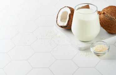 Glass of coconut milk and coconut close up on a white background with space for text. Coconut vegan milk non dairy or Dairy free milk concept. Healthy vegan food.