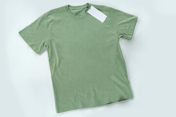 Green t-shirt laying on the table, top view, full body with a blank sign of the logo hanging.
