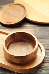 Different wooden plate and trays on brown wooden background. Vertical photo