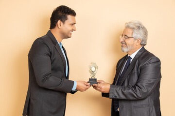 Happy indian boss gives award to his employees as an appreciation for his business success. Senior...