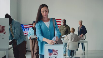 Full shot from ballot box on US state election day, of beautiful young Caucasian woman, African American man, Muslim lady in hijab casting their papers after voting in booth with emblem of USA flagFul - Powered by Adobe
